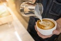 Close up of barista hand pouring stremed milk into white cup of hot coffee to create latte art Royalty Free Stock Photo