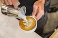 Close up of barista hand pouring stremed milk into white cup of hot coffee to create latte art Royalty Free Stock Photo