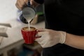 Close up barista pouring steamed milk into coffee cup making beautiful latte, cappuccino art Rosetta pattern. Close up barista