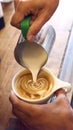 Close Up Of Barista Pouring Steamed Milk Into Cup Of Coffee In Cafe Making Foam Art Decoration 