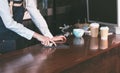 Close up barista waitress wear jean apron using tablet on count