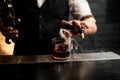 Close-up. Barman`s hand pours smoky drink from jigger into glass with ice Royalty Free Stock Photo