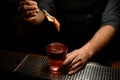 Close-up of bartender adding slice of orange zest in cocktail