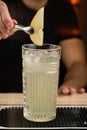 close-up of a bartender decorating an alcoholic cocktail with a piece of pear on a bar counter