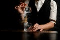 Close-up. Bartender gently holds in hand tweezers with ice over steaming glass
