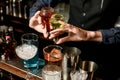 Close-up bartender holds bottles with liquor and adds it to glass with cocktail Royalty Free Stock Photo