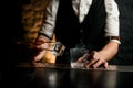 Close-up. Bartender holds in hand tweezers with ice near steaming glass