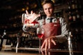 Close up bartender pouring bright red alcohol cocktail into fancy glass