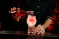 Close-up bartender pouring drink to glass full of pieces of ice. Royalty Free Stock Photo