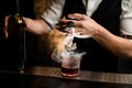 Close-up. Bartender`s hand pours smoky drink from jigger into glass with ice Royalty Free Stock Photo