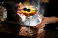 Close-up. Bartender sprinkles on glass with cocktail which decorated small sword with cherries
