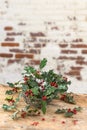 Close up basket of holly red berries branches, grean leaves, evergreen, on rustic, table over a , vintage ambiance
