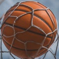 a close-up of a basketball going through a basketball net.The basketball is orange,