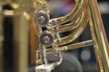 Close-up of a bass trombone tube with a fourth and fifth valve. Whorls in golden brass metal. Jazz trombones detail view with