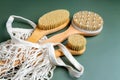 Close up of a bath bamboo brushes for dry massage in cotton mwsh bag on green background. Home spa and relaxation tools.