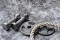 Close up of battle rope and dumbbells on a gray backgound. Sport and fitness equipment. Functional training