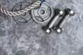 Close up of battle rope and dumbbells on a gray backgound. Sport and fitness equipment. Functional training