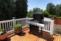 Close up of an BBQ cooker with lid open displaying smoke coming out while on home outdoor wooden deck