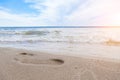 Close-up of the beach shore with a man`s footprint on the yellow sand along the line of the blue sea wave on a summer sunny day. Royalty Free Stock Photo