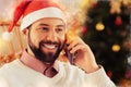 Close up of beaming happy dark-eyed man wearing New year hat calling wife