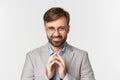 Close-up of bearded businessman in glasses and suit, scheming something, smiling devious and having perfect plan