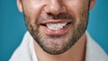 Close up of bearded man smiling at camera with toothpaste in his mouth after brushing teeth isolated over blue Royalty Free Stock Photo