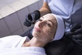 Close up of beautician applies ampoule cream in black gloves to face of female client in spa salon