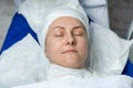 Close-up beautician doctor hands making anti-age procedures, applying foam cleansing mask for mid-aged female client at Royalty Free Stock Photo