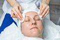 Close-up beautician doctor hands making anti-age procedures, cleaning with napkins facial mask for mid-aged female Royalty Free Stock Photo