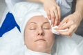 Close-up beautician doctor hands making anti-age procedures, cleaning with napkins facial mask for mid-aged female Royalty Free Stock Photo