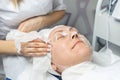 Close-up beautician doctor hands making anti-age procedures, cleaning with napkins facial mask for mid-aged female Royalty Free Stock Photo