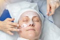 Close-up beautician doctor hands making anti-age procedures, facial and head massage for mid-aged female client at beauty clinic.