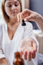 Close up of a beautician hand apply serum from a pipette on the wrist of a female client indoors