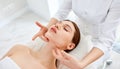 Therapist doing myofascial or buccal massage on face and head for female client lying at beauty center or spa salon Royalty Free Stock Photo