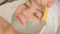 Close-up beautician puts alginate mask of green algae on the face of Asian girls. Mask with lifting effect for women. Cosmetic