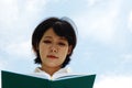 Asia woman holding and reading book on sky background. Royalty Free Stock Photo