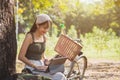 Close up Beautiful Asian woman in casual wear sitting and using a laptop under the tree next to a white bicycle in a public park Royalty Free Stock Photo