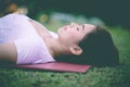 Close up Beautiful Attractive Asian woman practice yoga Dead Body pose or Savasana pose lying on yoga mat with green grass for yog Royalty Free Stock Photo