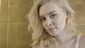 Close up for a beautiful blond girl with perceptive look over the background of golden wall tiles. Action. Young Royalty Free Stock Photo