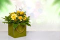 Close-up of a beautiful bouquet with yellow flowers in a decorative green gift box on a bright table over abstract spring Royalty Free Stock Photo