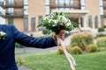 Close up of beautiful bridal bouquet of white and cream flowers and greenery in groom& x27;s hand outdoors, copy space. Royalty Free Stock Photo