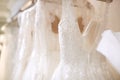 Close Up Of Beautiful Bridal Wedding Dresses Hanging On Rail In Shop 