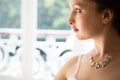 Beautiful bride wearing necklace looking through window at home Royalty Free Stock Photo