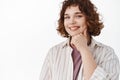 Close up of beautiful candid girl with curly short hair, smiling with white teeth and looking thoughtful at camera