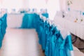 Close-up of beautiful chairs decorated by blue fabric in the restaurant. Wedding hall decorations with blurred background