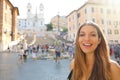 Close up of beautiful cheeful woman in Piazza di Spagna square in Rome with Spanish Steps and Barcaccia fountain on the background