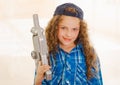 Close up of beautiful curly girl wearin boy clothes and holding in her hands a toy gun