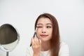 Close up of beautiful face of asian young woman getting make-up. Asian woman is applying eyeshadow on her eyebrow with brush. Royalty Free Stock Photo
