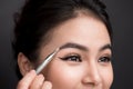 Close up of beautiful face of young asian woman getting make-up. The artist is applying eyeshadow on her eyebrow with brush Royalty Free Stock Photo