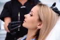 Close-up beautiful female face and cosmetologist`s hands with syringe during facial beauty injections. Rejuvenation and Royalty Free Stock Photo